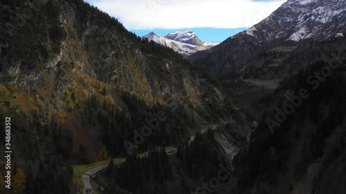 Aerial footage of majestic rocky mountains with trees during winter, drone moving towards mountain range - Hochtannberg Pass, Austria photo