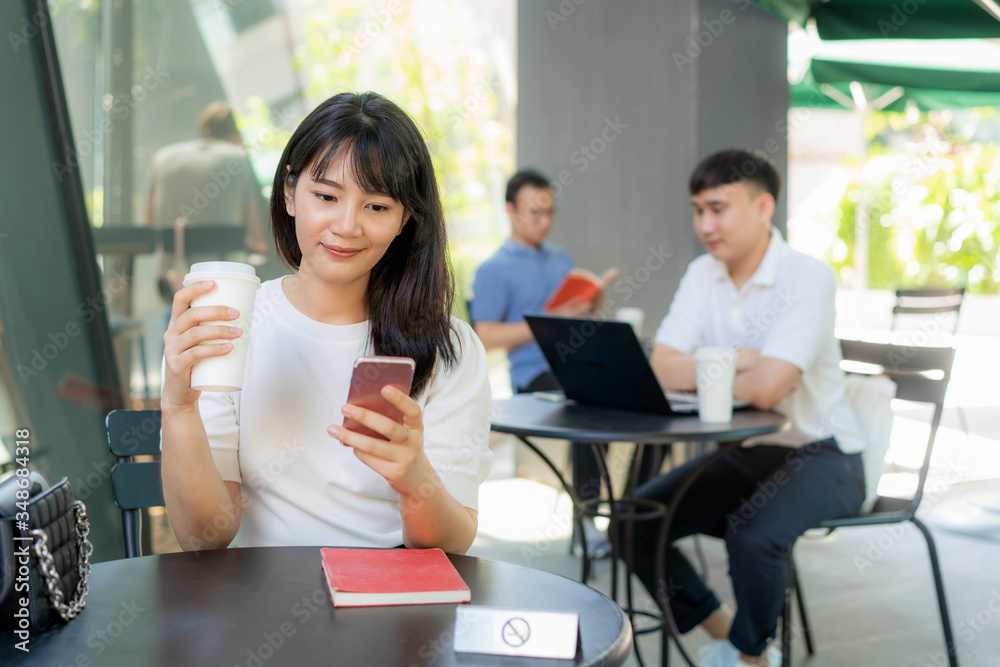 Asian young man and woman sitting one person per one table for distance of 6 feet distance protect from COVID-19 viruses for social distancing for infection risk at coffee cafe.. Asian young man and woman sitting one person per one table for distance of 6 feet distance protect from COVID-19 viruses for social distancing for infection risk at coffee cafe..