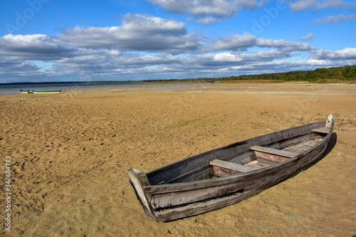 Wooden fising boats on the drying lake bed. Natural disaster  Blue sky background. 