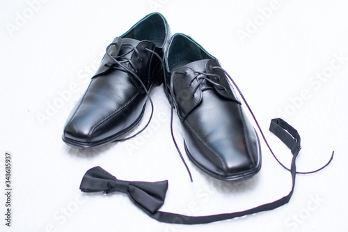 Black dress shoes for men and in front of the shoes a black bow tie.