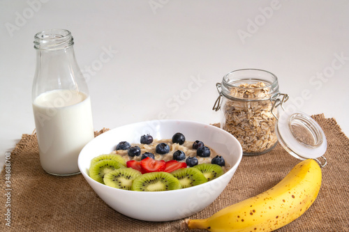 oatmeal with fruits on a white background and a glass bottle of milk