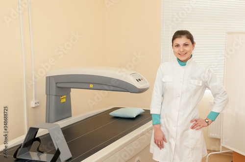A female doctor stands next to a densitometer. Densitometry in the clinic. Medical equipment photo