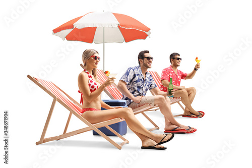 Young people sunbathing on beach chairs and holding drinks
