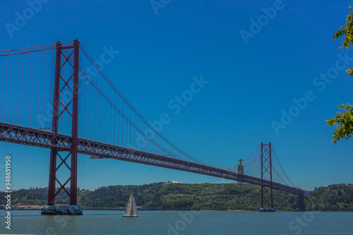 Ponte de 25. april in Lisbon  portugal  taken on a sunny day. A small sailboat is just passing under the bridge.