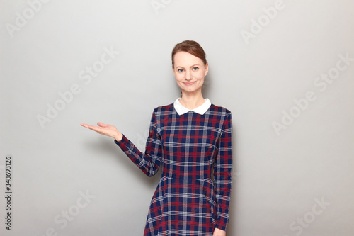 Portrait of cheerful young woman pointing with hand at copy space