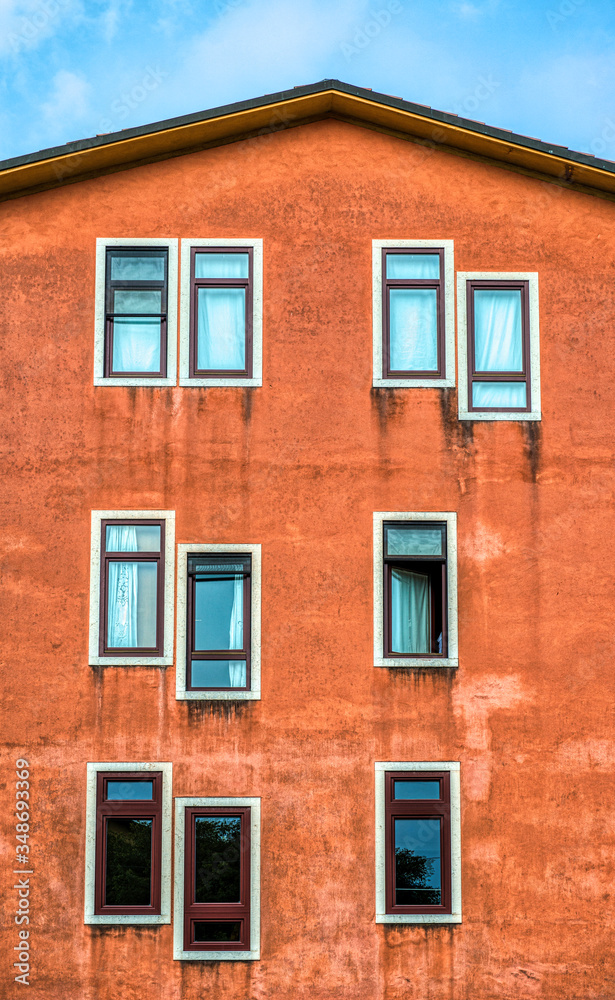 An orange apartment building in Verona Italy with windows in odd placements 