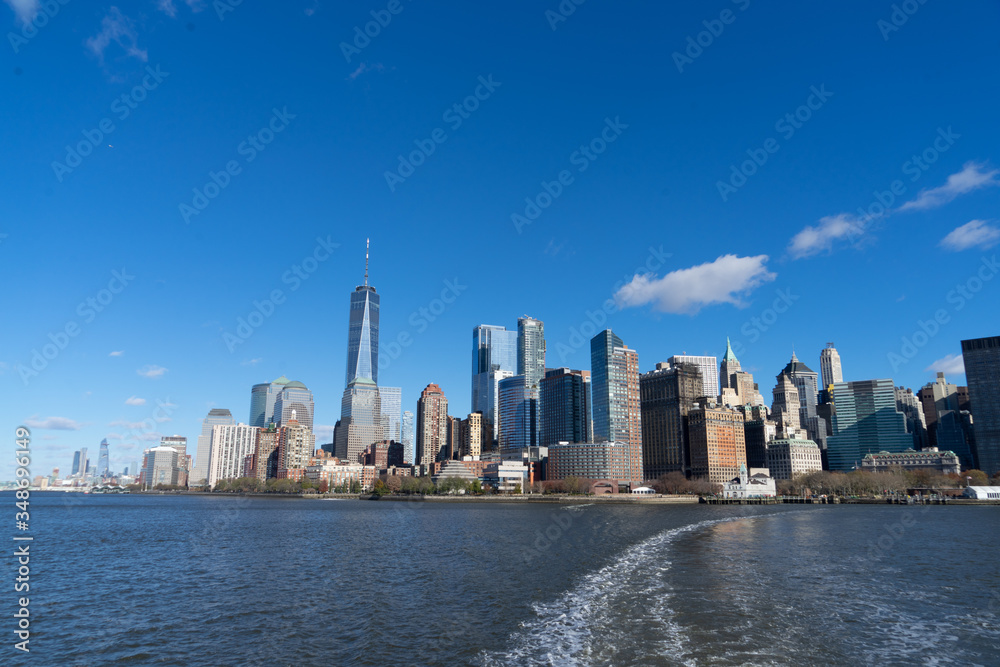 view of Manhattan New York from the hudson river and boat heading to statue of liberty