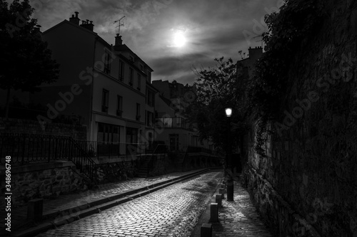 Fototapeta Naklejka Na Ścianę i Meble -  Paris, France - May 12, 2020: Small dark street on the Montmartre hill in Paris, a full moon night