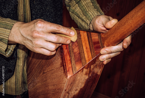 Slika na platnu polishing wooden musical instrument with sponge, oriental stringed instrument lavta being polished with shellac, closeup