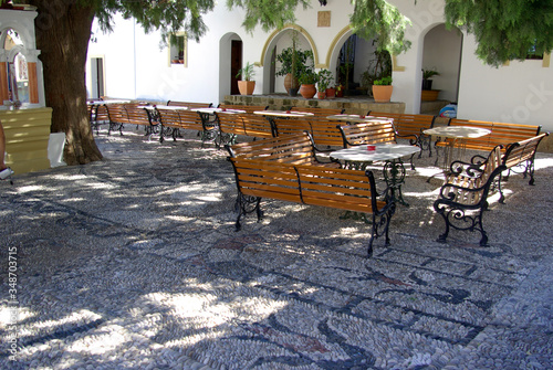 Empty benches and tables on the street in a Greek village