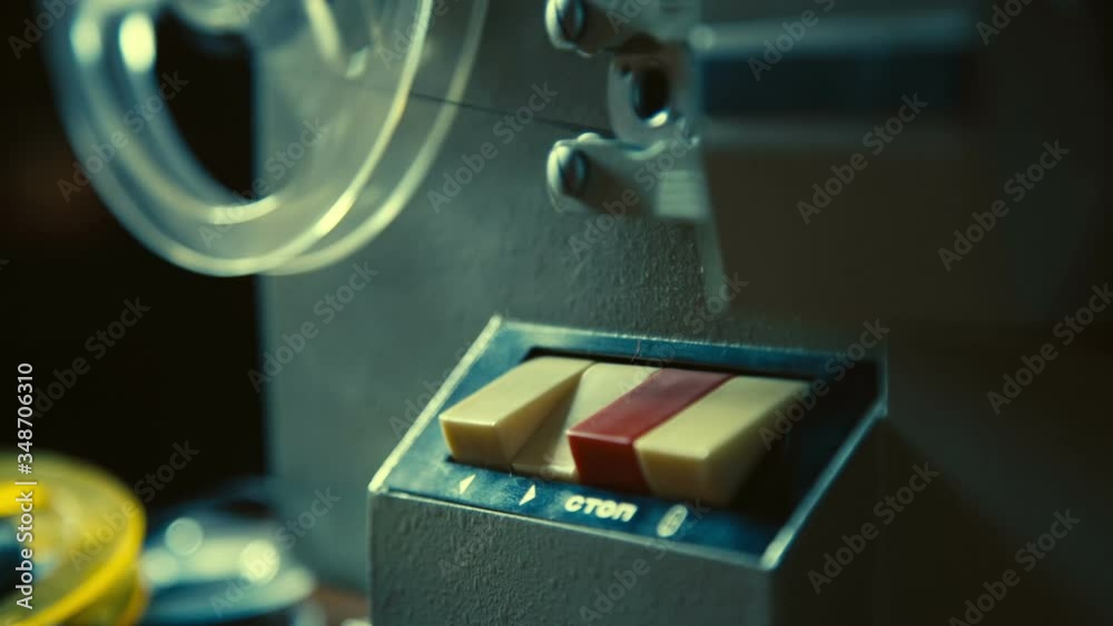 Male hand presses button on old movie projector to test it before watching old movie record, the film reel is starting to rotate, Slow motion.