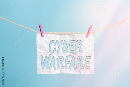 Handwriting text Cyber Warfare. Conceptual photo Virtual War Hackers System Attacks Digital Thief Stalker Clothesline clothespin rectangle shaped paper reminder white wood desk photo