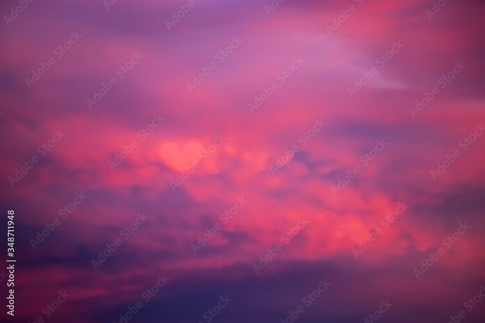 Beautiful sky at sunset. Purple and pink unusual heart clouds. Blurred background for design.