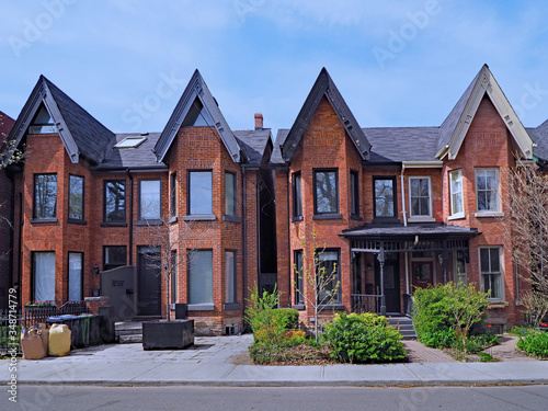 Residential street with narrow brick Victorian style houses with gables