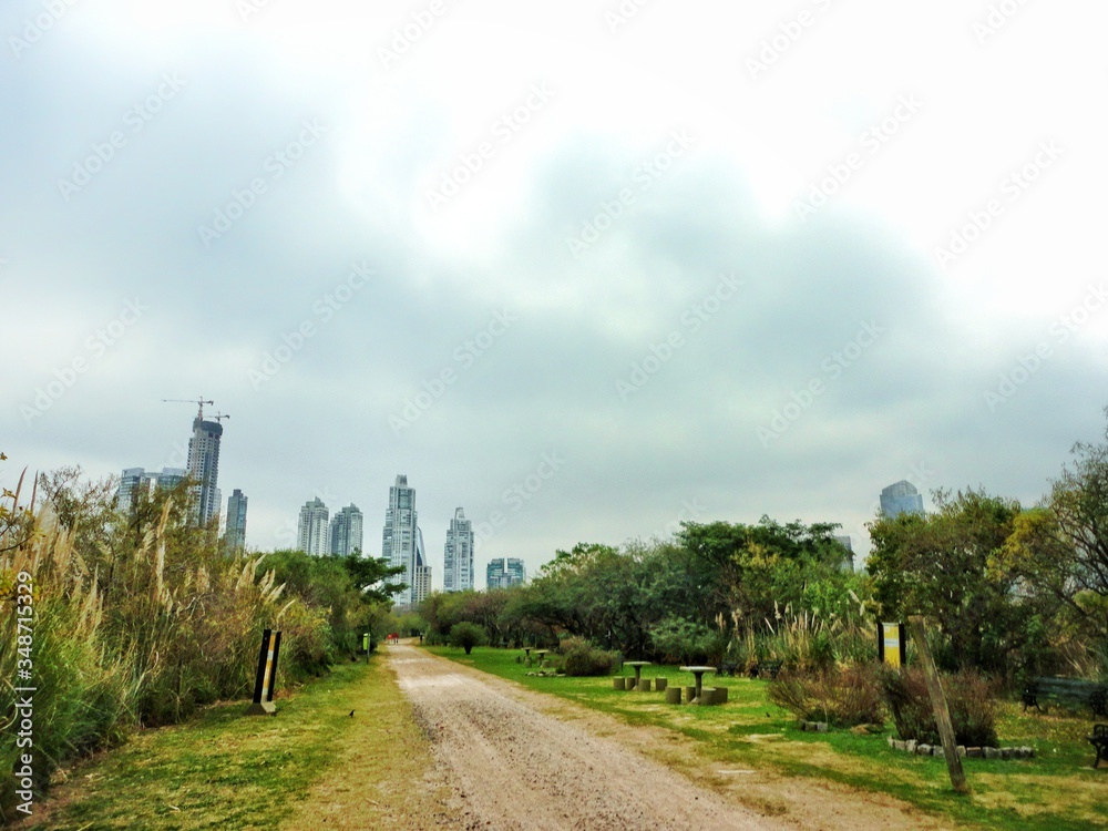 Trails of the ecological reserve with the greens on the side and the buildings in the background