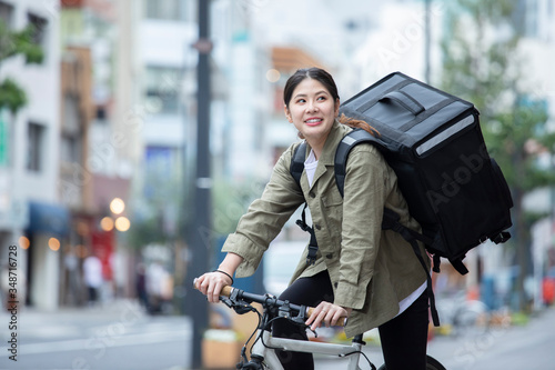 自転車で荷物の配送を行う若い女性 © west_photo