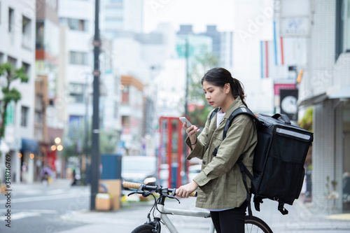 自転車で荷物の配送を行う若い女性 © west_photo