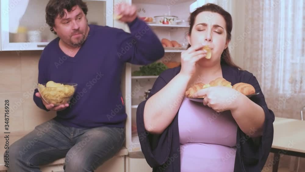 Overweight husband and wife eat at night not healthy food about the diet. Overweight