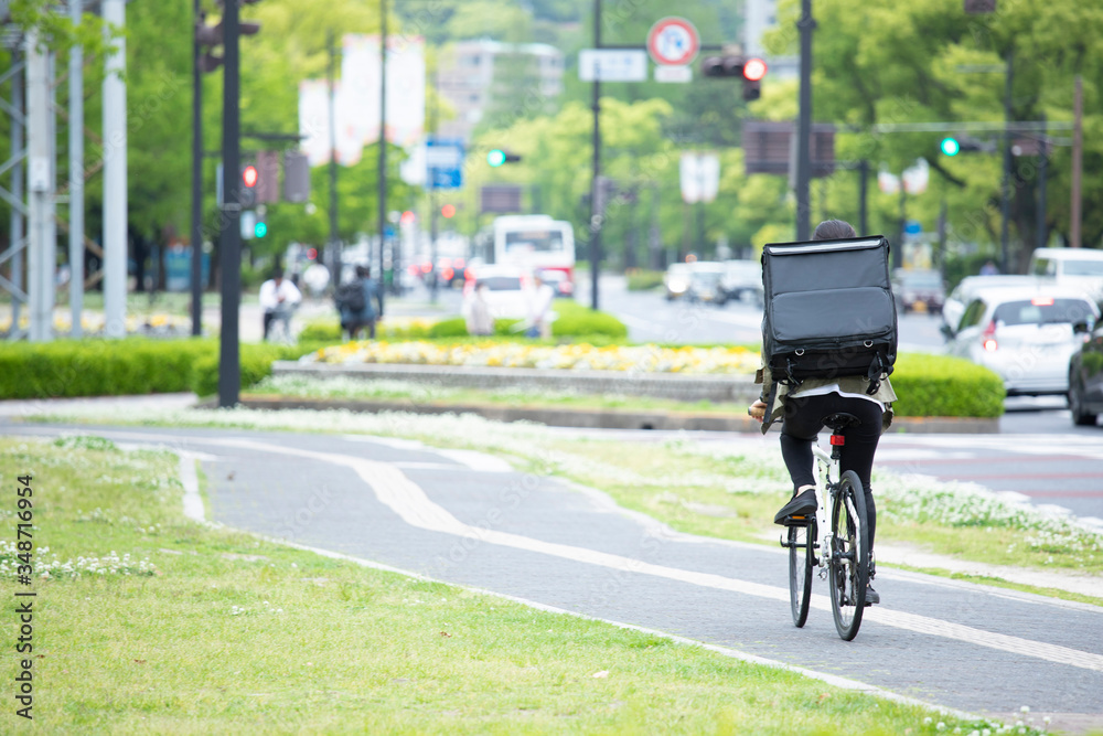 Fototapeta premium 自転車で荷物の配送を行う若い女性