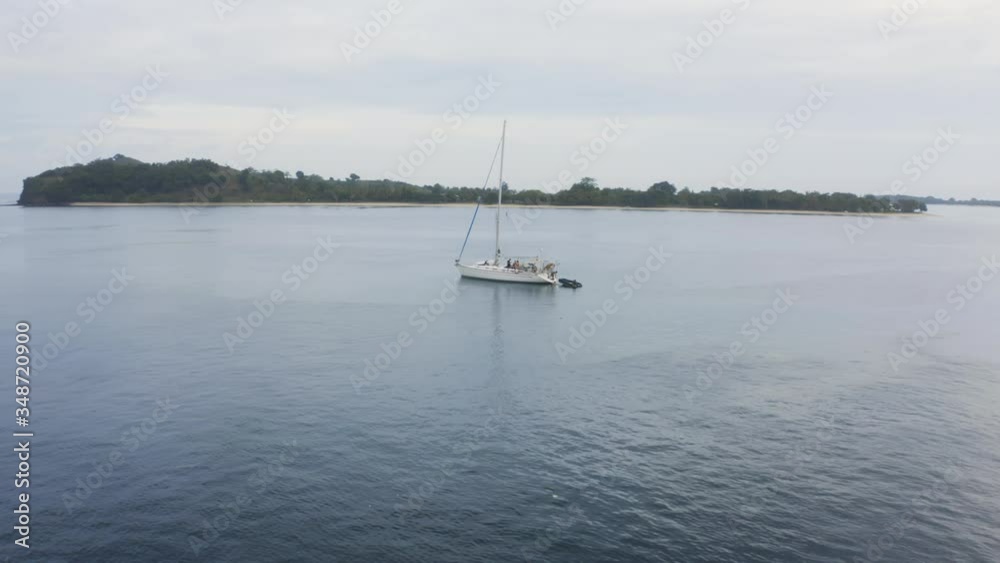 Aerial view of sailing boat anchoring next to island Aerial view of sailing boat anchoring next to island