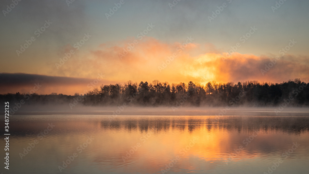 Sunrise on a foggy morning featuring a tree line at Lake