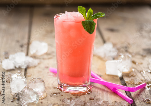 Cold and icy red grapefruit drink with ice around
