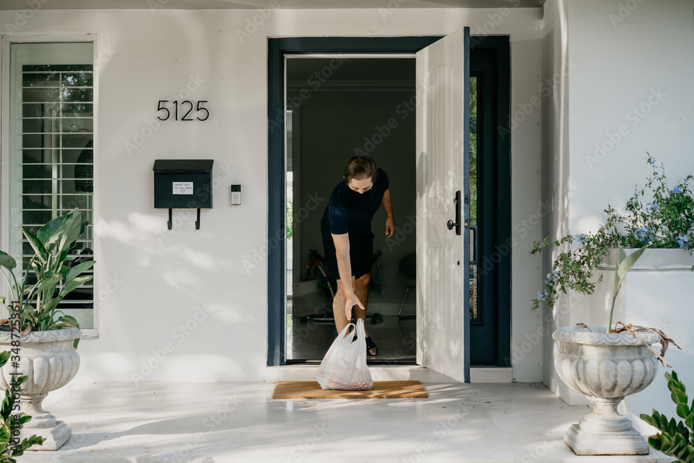 Man at home with a mask receiving food delivery Man at home with a mask receiving food delivery