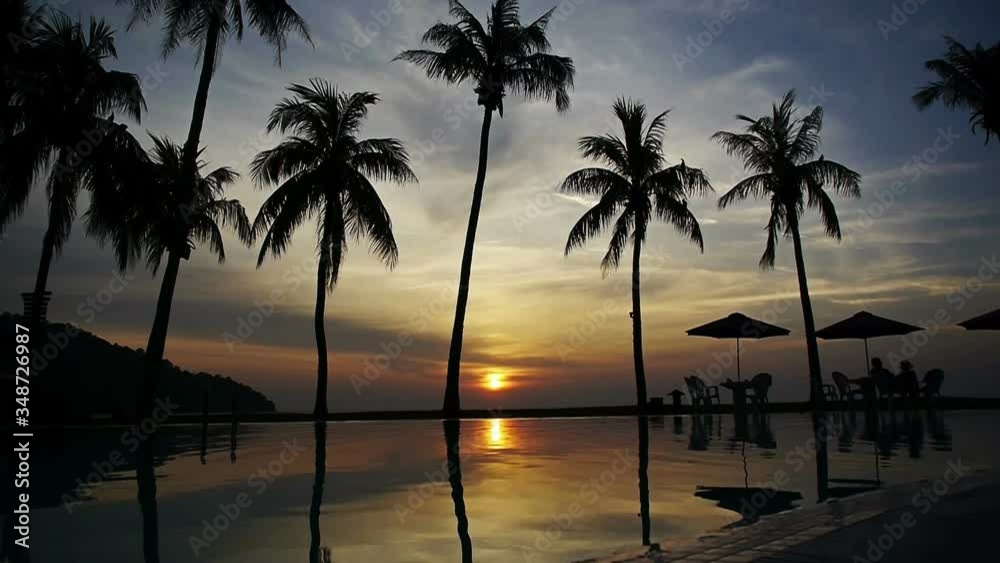 Sun setting reflected in pool water under the palm trees in a tropical resort 1 Sun setting reflected in pool water under the palm trees in a tropical resort 1