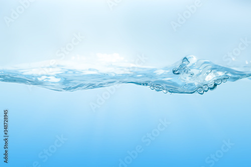 Water splash on blue background. Aqua flowing in waves and creating bubbles. Drops on the water surface feel fresh and clean.