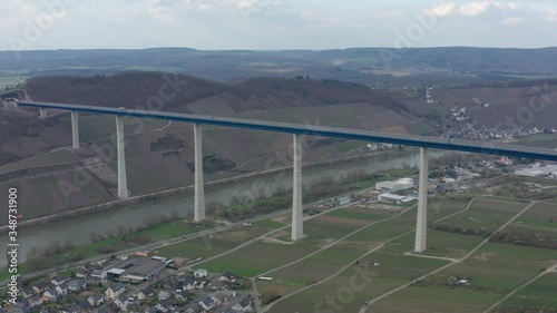 Hochmoselbrücke High Moselle Bridge in Rhineland-Palatinate Germany with cars and trucks on a freeway highway cinematic panorama aerial drone shot on a sunny cloudy day 30p photo