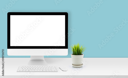 Mockup desktop computer display blank screen on desk in office, workspace with mock up computer screen empty and keyboard, mouse, plant and copy space on table in home, business presentation concept.