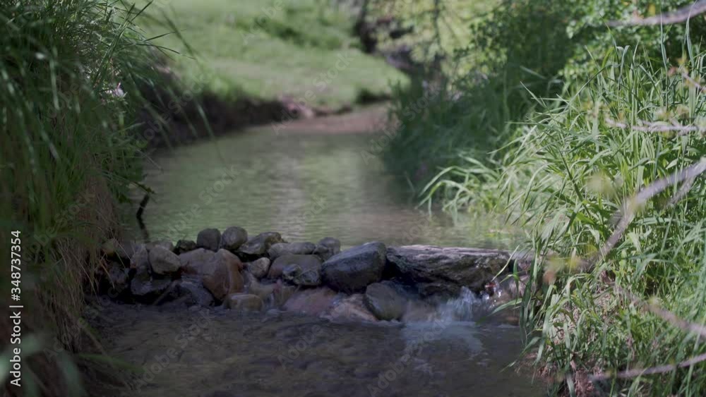 Water from a pastoral stream flows over a small rock bridge on a beautiful sunny day. Water from a pastoral stream flows over a small rock bridge on a beautiful sunny day.