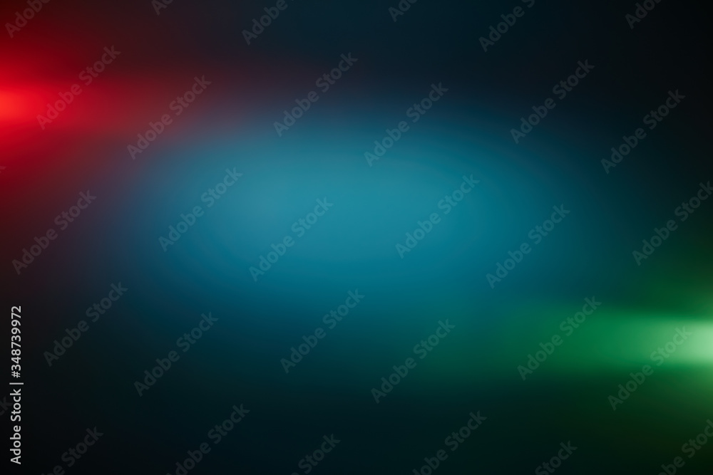 Green and red rays of light around a dark turquoise volumetric cloud of light