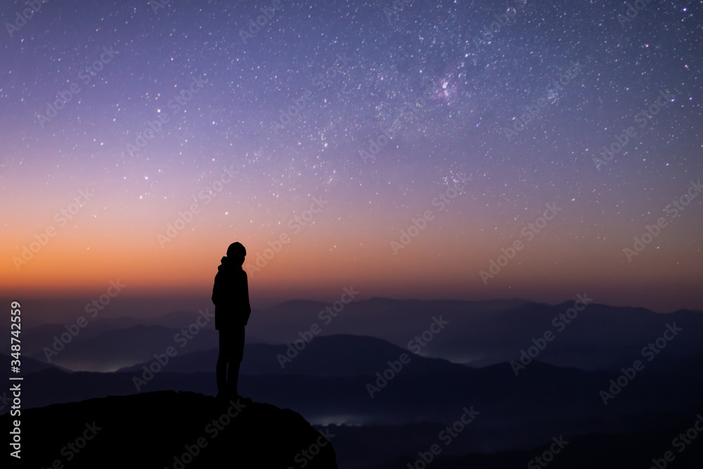 Silhouette of young traveler watched the star and milky way on top of the mountain alone before sunrise. He is happy to be with herself and stay with nature at twilight time.
