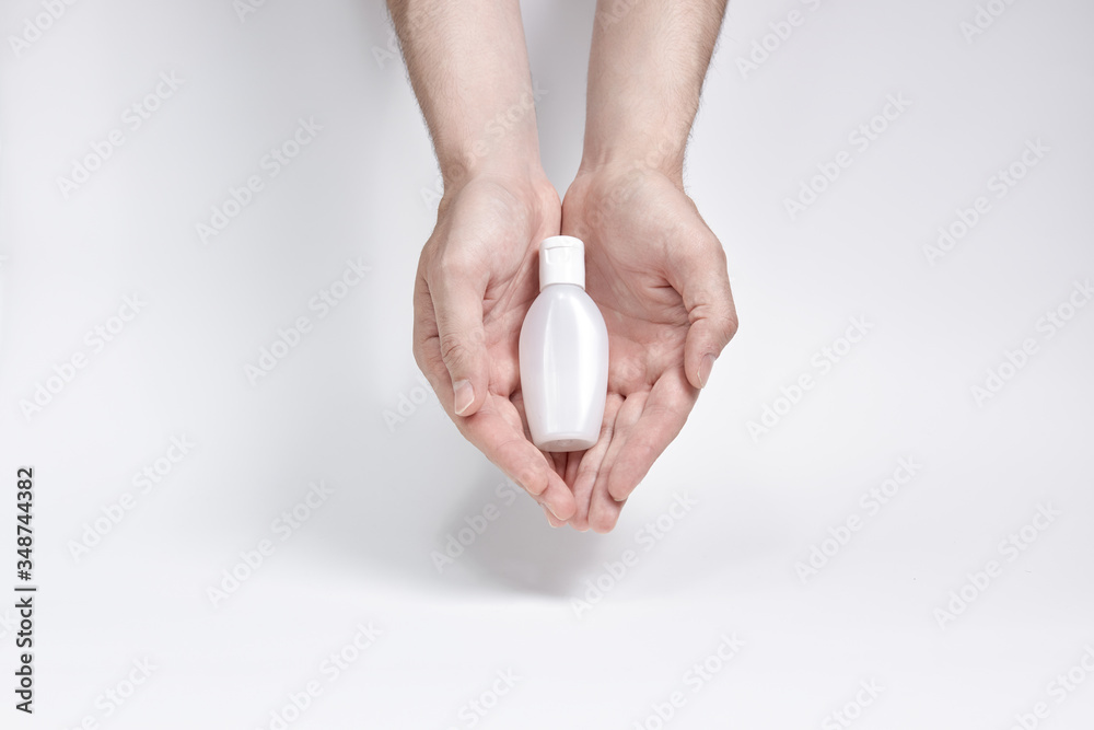 a small bottle for cream, liquid or antiseptic in two hands on a white background. copyspace a small bottle for cream, liquid or antiseptic in two hands on a white background. copyspace