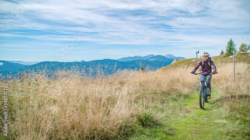 Couple Mountain Biking Across Grassland On Mount St. Ursula. Slow Motion, Follow Shot photo