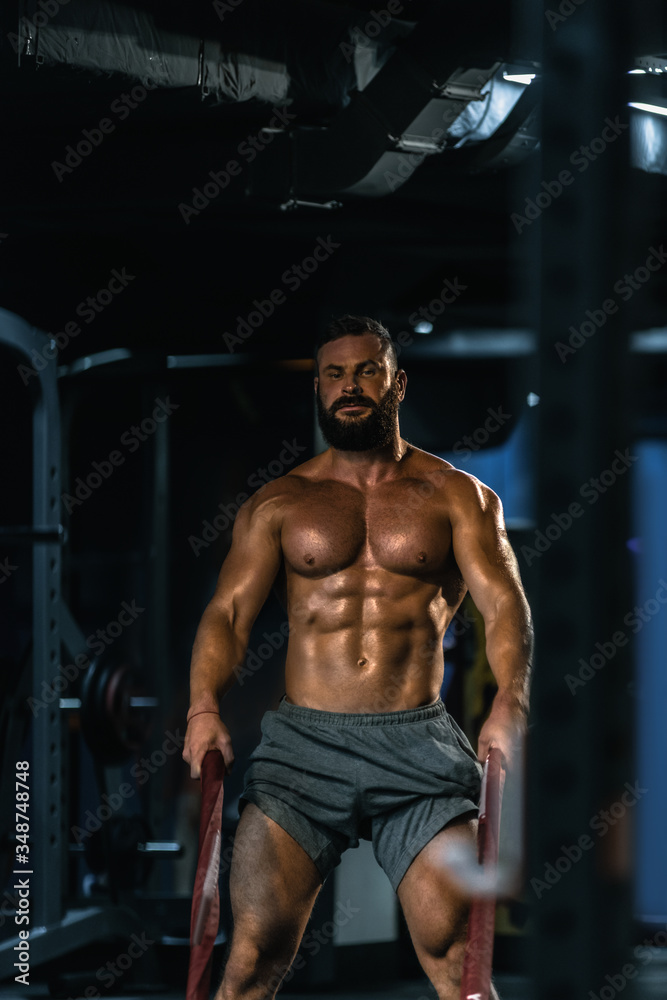 Fit athletic bodybuilder pulling heavy battle rope