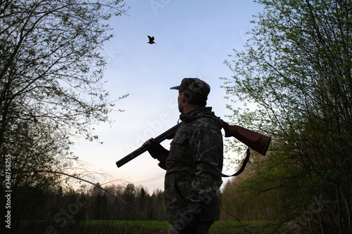 Fototapeta a hunter looks at a flying woodcock late at night