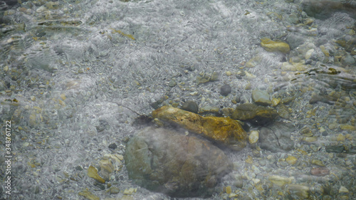 Mountain river with clear water, waves on the surface of the water, transparent bottom. Stones in the river.