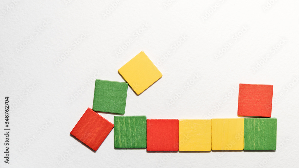 Obraz premium Different colorful squares wooden on white background. Geometric shapes red, green, yellow colors, top view. Concept of geometry. Copy space. Children educational logical task. Flat lay.