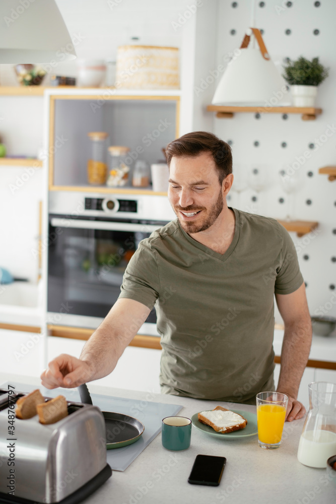 Handsome man preparing breakfast at home. Young man drinking coffee in kitchen. Handsome man preparing breakfast at home. Young man drinking coffee in kitchen.