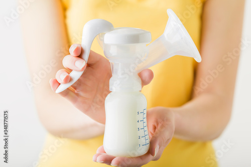 Young mother hands holding plastic breast pump bottle. Closeup. Preparing milk for baby feeding. Front view.