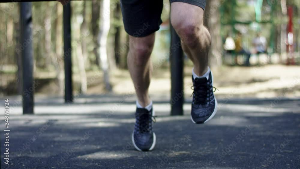 Adult caucasian athlete is running on the sport at the bars topless during his daily workout at the gym at the park, close up Adult caucasian athlete is running on the sport at the bars topless during his daily workout at the gym at the park, close up