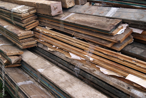 Bundles of old boards are tied with transparent tape and stacked in a pile