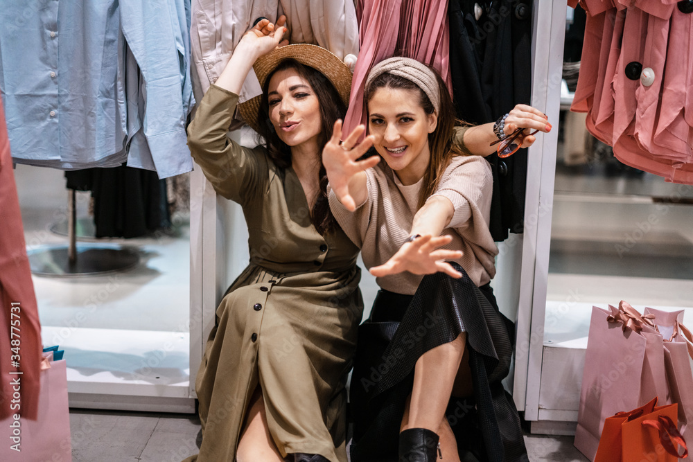 Obraz premium Trade, buyers. Two beautiful girls make purchases in a shopping center, go shopping. The joy of consumption.