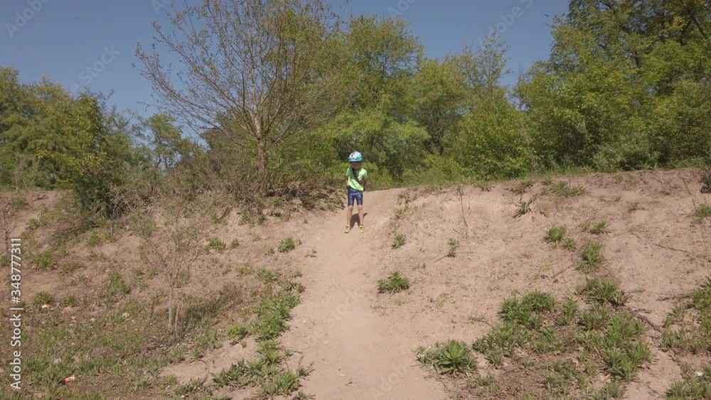 Little boy with helmet running down a hill in slow motion in Germany on a sunny day Little boy with helmet running down a hill in slow motion in Germany on a sunny day