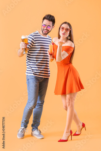 Happy young couple with alcoholic drinks on color background © Pixel-Shot
