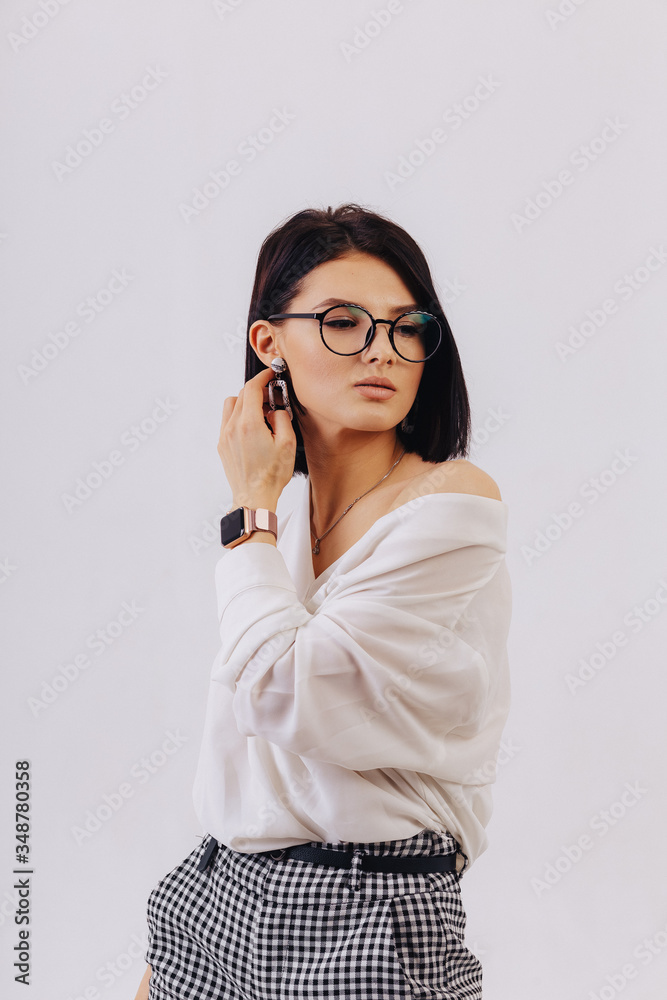 attractive stylish young girl in business clothes posing on light background in studio. concept of stylish clothes and sophistication.