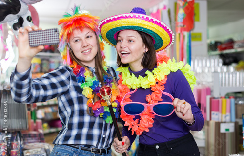 Girls making funny selfies photo in festive accessories shop