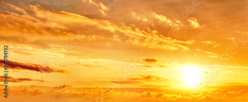 dramatic sunset sky landscape background. Natural color of evening cloudscape with setting sun. Orange clouds on yellow sky. Colorful panorama wallpaper. Ultra wide panoramic view. Banner template © vaalaa